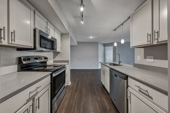 A modern kitchen with dark wood floors and white cabinetry.